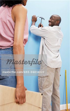 Couple handing pictures on interior wall, back view