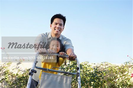 Girl (7-9) helfen Vater mähen Rasen, Porträt, Flachwinkelansicht