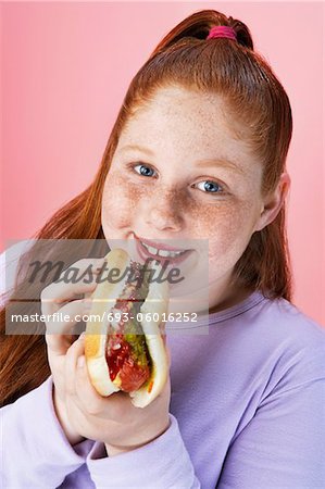 Overweight girl (13-15) Eating hot dog, portrait, close-up