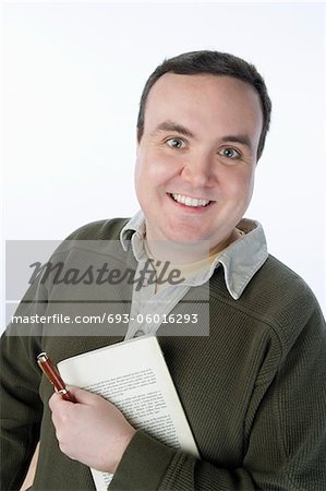 Portrait of mid-adult man holding pen and book