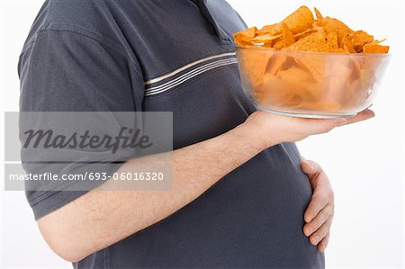 Mid-adult man holding glass bowl of potato chips, mid section