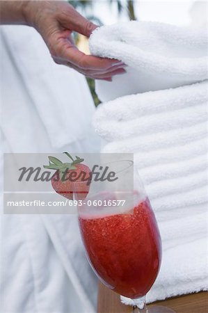 Senior woman holding towel near strawberry cocktail, close-up