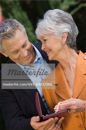 Senior man with senior woman holding pearl necklace