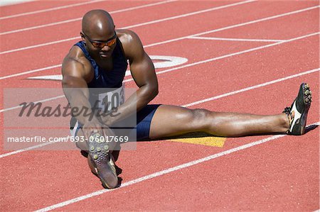 Male sprinter stretching on track