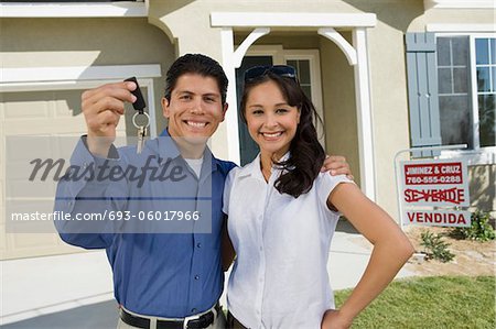 Jeune couple de clés de tenue à l'extérieur de la nouvelle maison, portrait