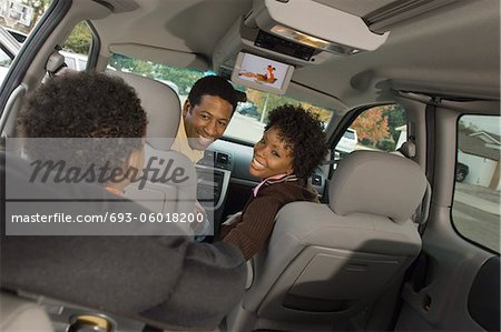 Couple smiling at young son in car