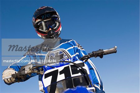 Pilote de motocross sur vélo contre le ciel bleu, (angle faible vue)