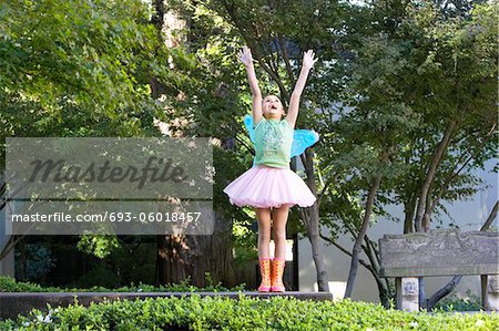 Girl wearing tutu and fairy wings playing in park