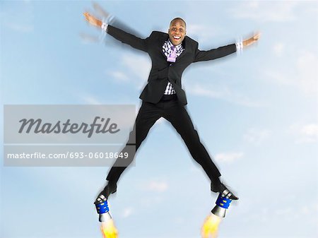 Man in suit jumping in star shape with rockets on feet, digital composite