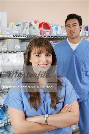 Infirmière mâle et femelle se tenant près des étagères avec des fournitures médicales, portrait