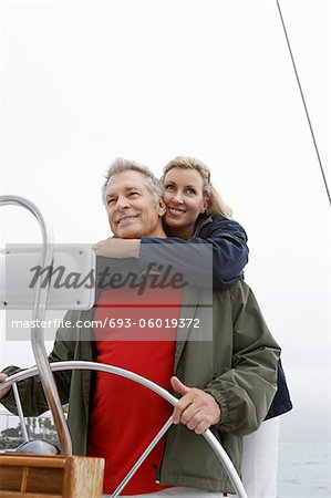 Couple at helm of sailboat, smiling