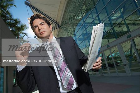 Homme d'affaires avec du papier journal à l'extérieur de l'immeuble de bureaux