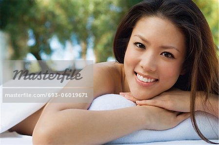 Young woman lying on massage table, outdoors, portrait