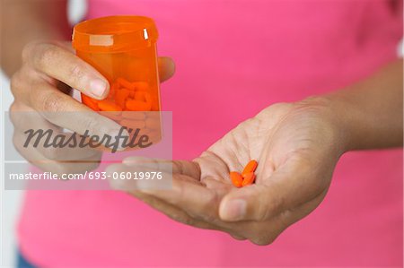 Woman's hands holding pills and bottle, close-up