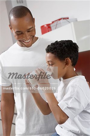 Father watching son (7-9) drinking milk, indoors