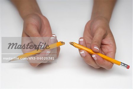 Woman holding broken pencil, close-up of hands