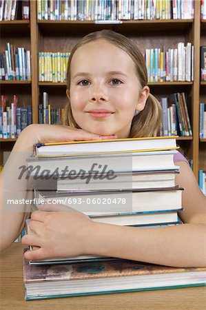 School girl hugging books in library, portrait
