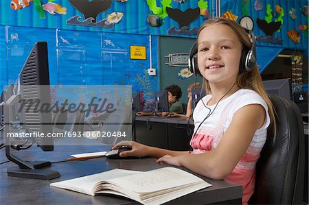 School girl wearing headphones in computer room, portrait