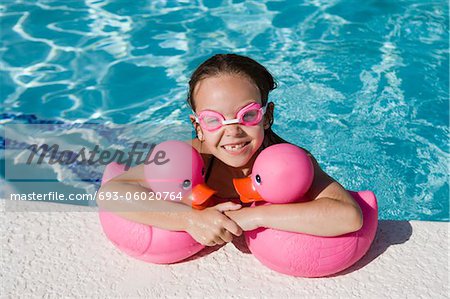 Jeune fille au bord piscine détenant des canards en caoutchouc rose
