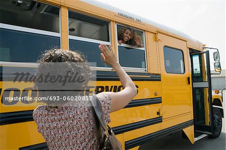 Mère saluant sa fille adolescente sur les autobus scolaires