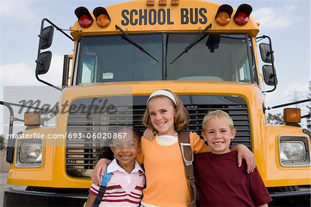 Élèves du primaire se tenant près des autobus scolaires