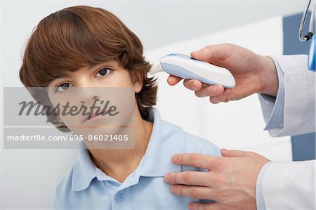 Boy having temperature taken with ear thermometer,portrait