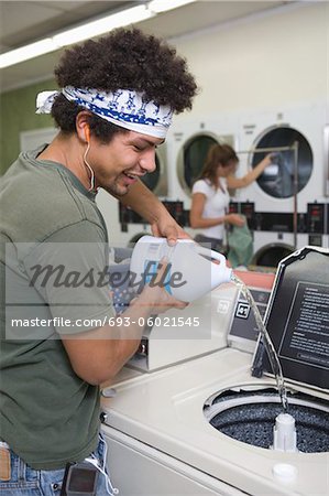 Young man washing clothes at launderette