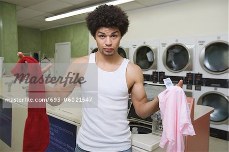 Young man washing clothes at launderette