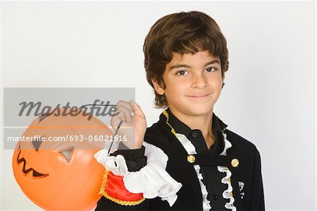 Portrait of boy (7-9) wearing Halloween costume, with jack-o-lantern