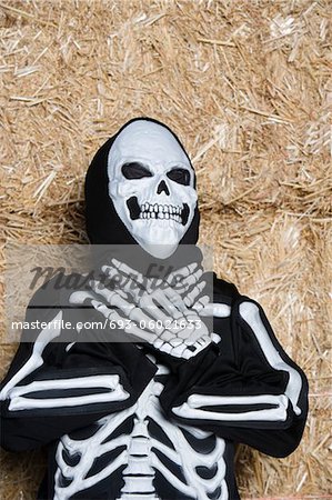 Portrait of child (7-9) wearing skeleton costume by hay