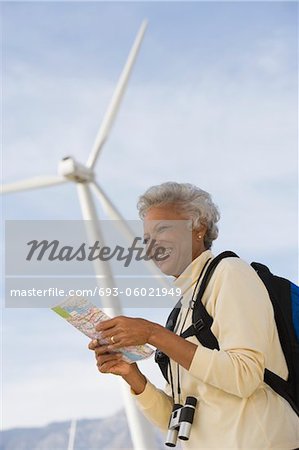 Mature woman with map by wind farm