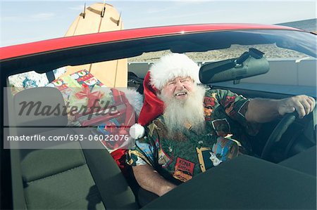 Weihnachtsmann sitzt im roten Cabrio mit Surfbrett