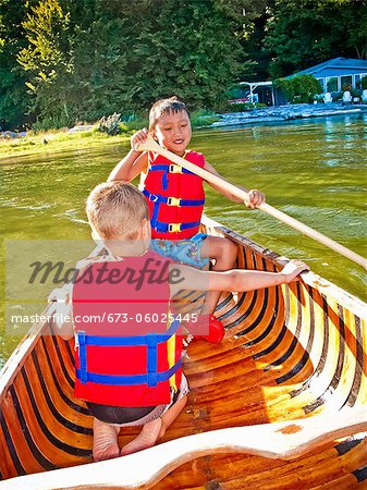 Two young boys paddling canoe