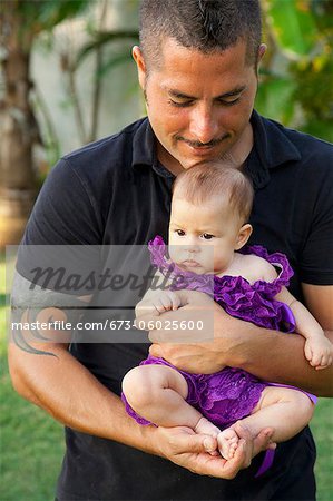 Mann in schwarzer Kleidung hält Baby-Mädchen
