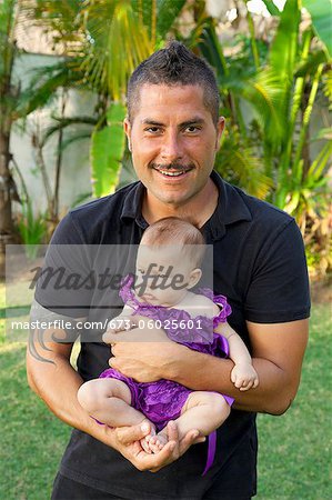 Man in black clothing holding baby girl