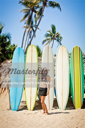 Woman in swimsuit in front of row of surfboards