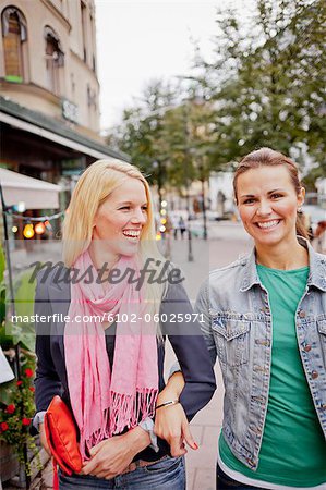 Zwei Frauen gehen Arm in Arm auf Pflaster