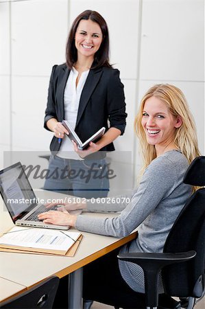 Two female colleagues posing together in office environment