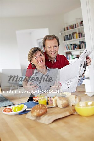 Mature couple reading newspaper during breakfast