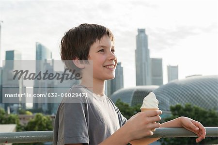 Junge hält Eistüte, im Hintergrund die Skyline der Stadt