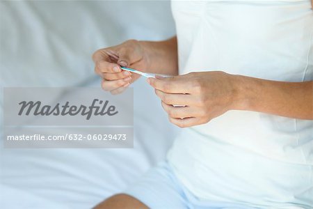 Woman holding pregnancy test, mid section