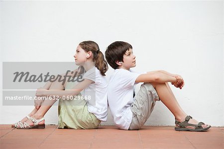 Boy and girl sitting back to back listening to music together