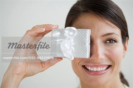 Woman holding gift in front of one eye