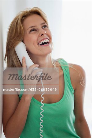 Young woman talking on landline phone, laughing