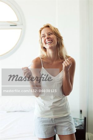 Young woman holding pregnancy test, laughing