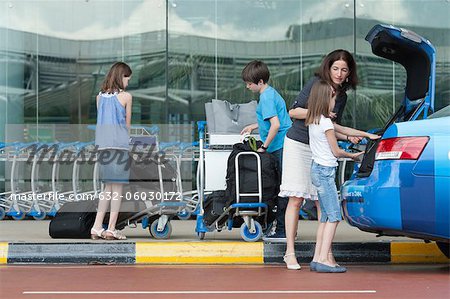 Famille à l'extérieur du bagage déchargement aéroport de tronc de taxi
