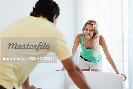 Young woman moving sofa with husband