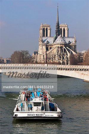 Tourist boat going under bridge on the River Seine, with Notre Dame Cathedral in background, Paris, France, Europe