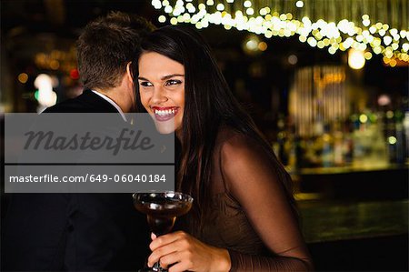 Smiling couple whispering at bar