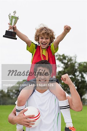 Coach carrying child with trophy